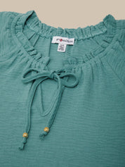 Teal top with ruffled neckline and tie detail, brand label visible.