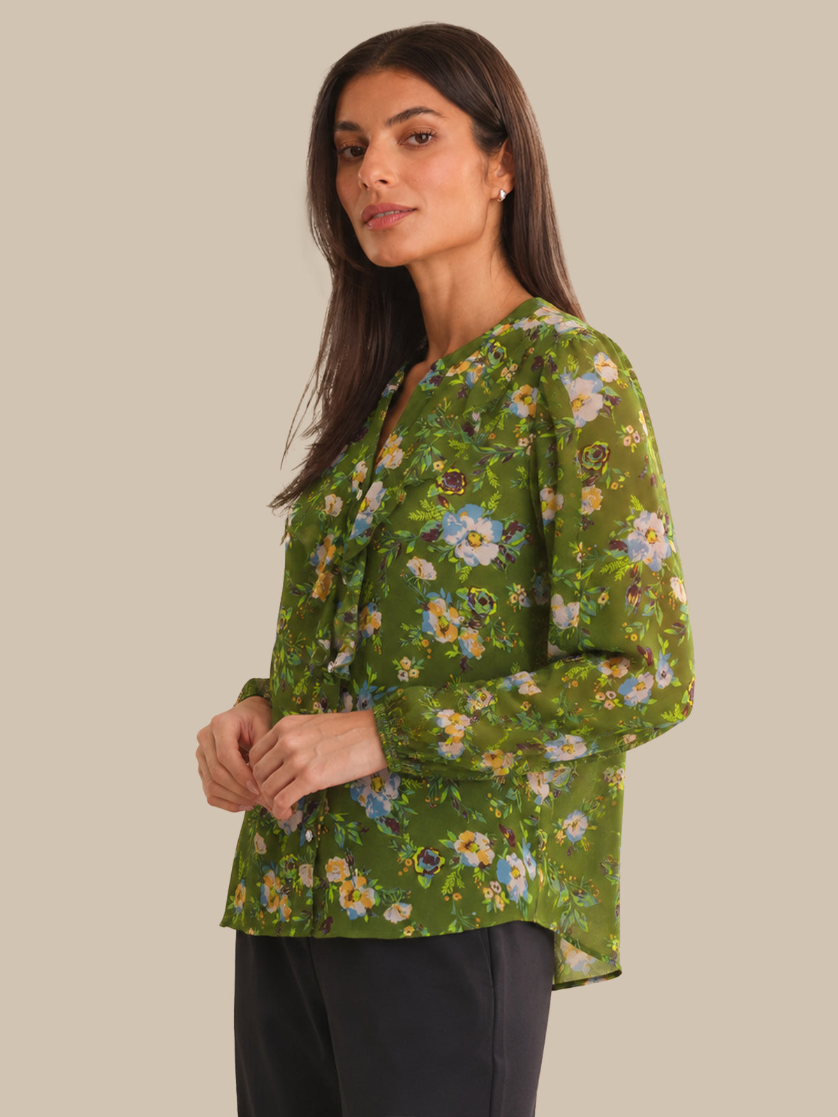 Woman wearing a green floral blouse against a beige background