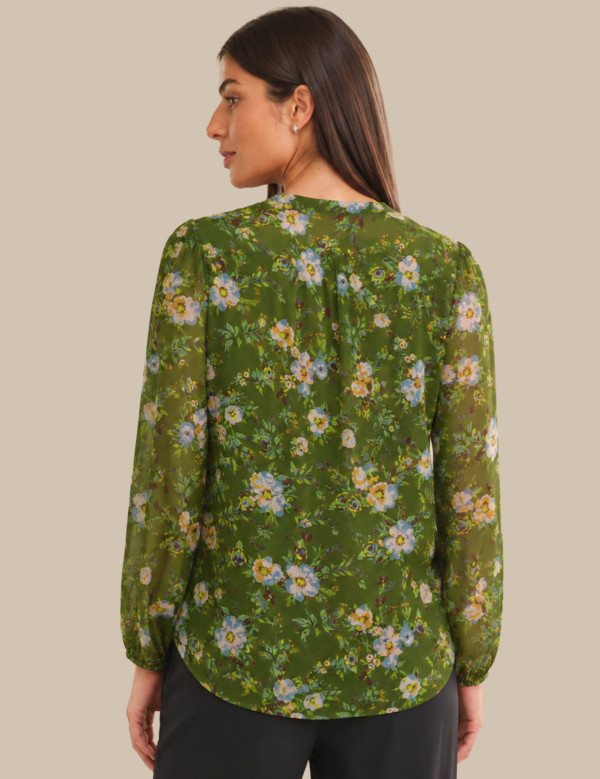 Woman wearing a green floral blouse against a beige background