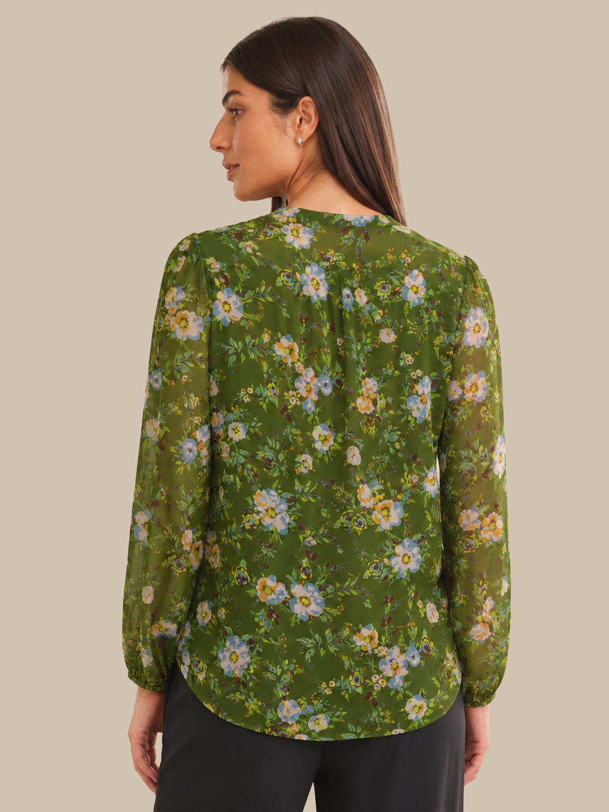 Woman wearing a green floral blouse against a beige background