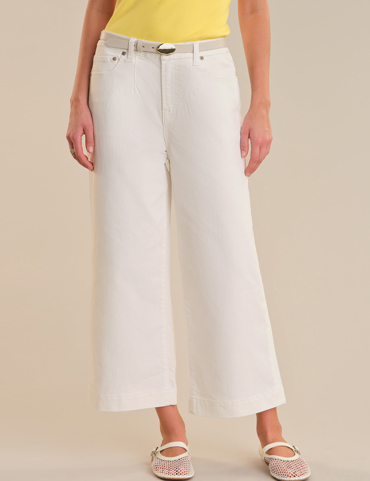 Person wearing white wide-leg jeans on a beige background