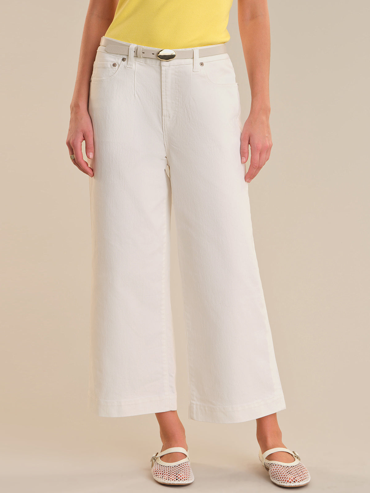 Person wearing white wide-leg jeans on a beige background