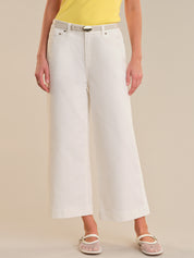 Person wearing white wide-leg jeans on a beige background