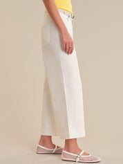 Person wearing white pants and fishnet sandals on a beige background