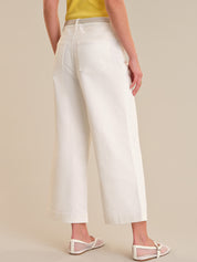 Person wearing white wide-leg pants on a beige background