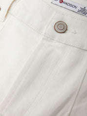 Close-up of a white denim pocket with a button and 'Madison' brand label.