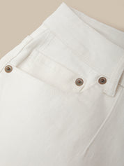 Close-up of a white denim jacket with brown buttons on a beige background