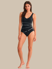 Woman wearing a black swimsuit with white patterns on a beige background