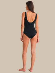 Woman wearing a black swimsuit on a beige background