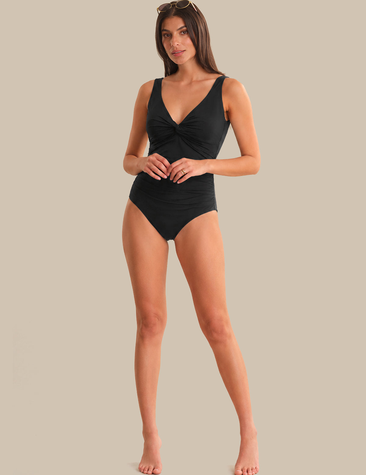 Woman wearing a black swimsuit against a beige background