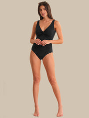 Woman wearing a black swimsuit against a beige background