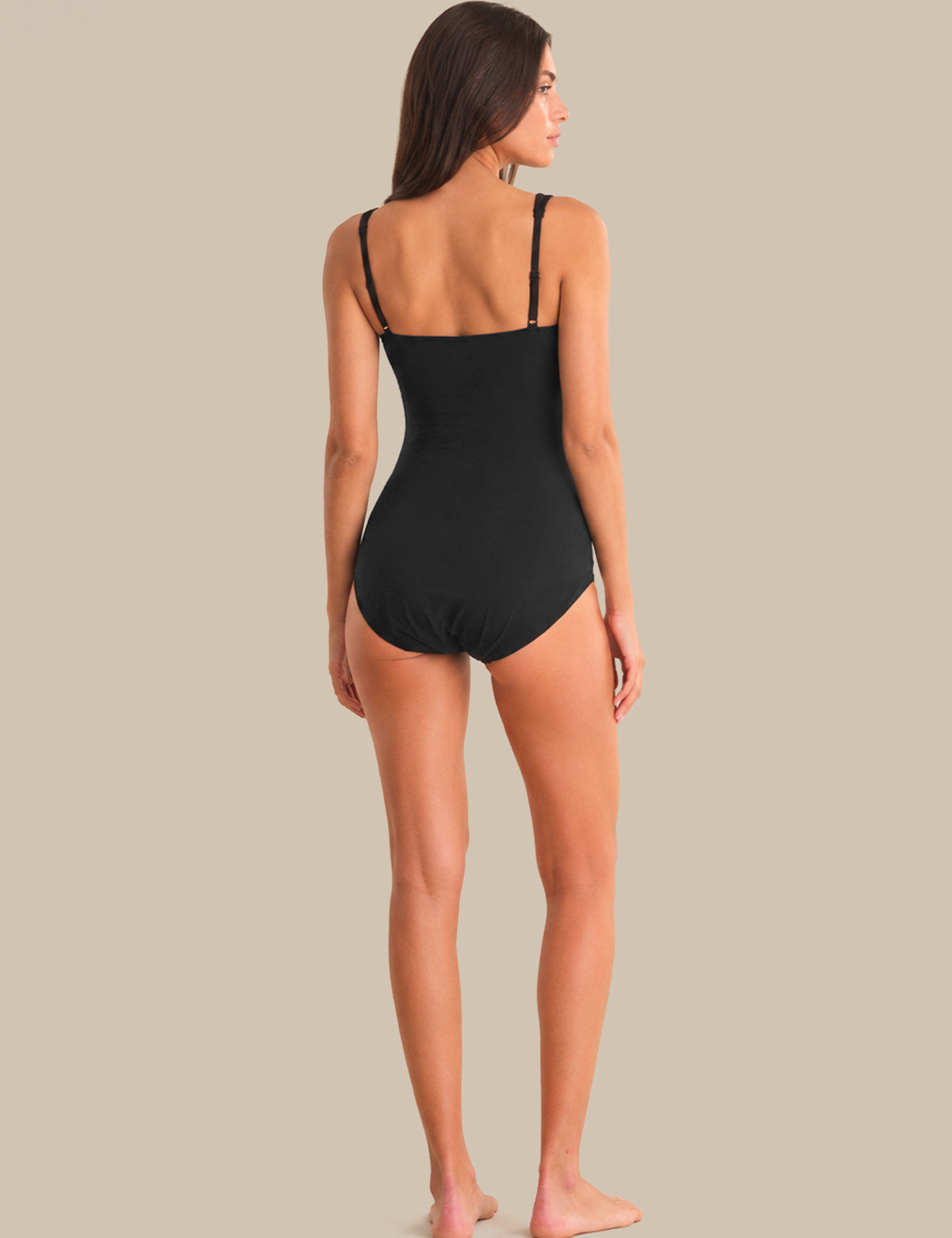 Woman wearing a black swimsuit against a beige background