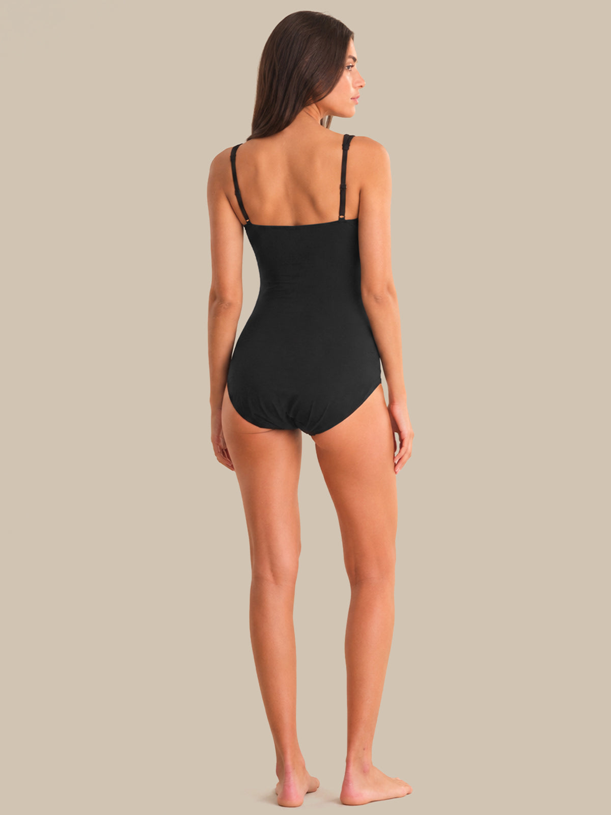 Woman wearing a black swimsuit against a beige background