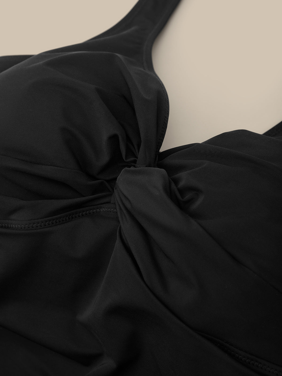 Close-up of a black garment with a bow detail on a beige background