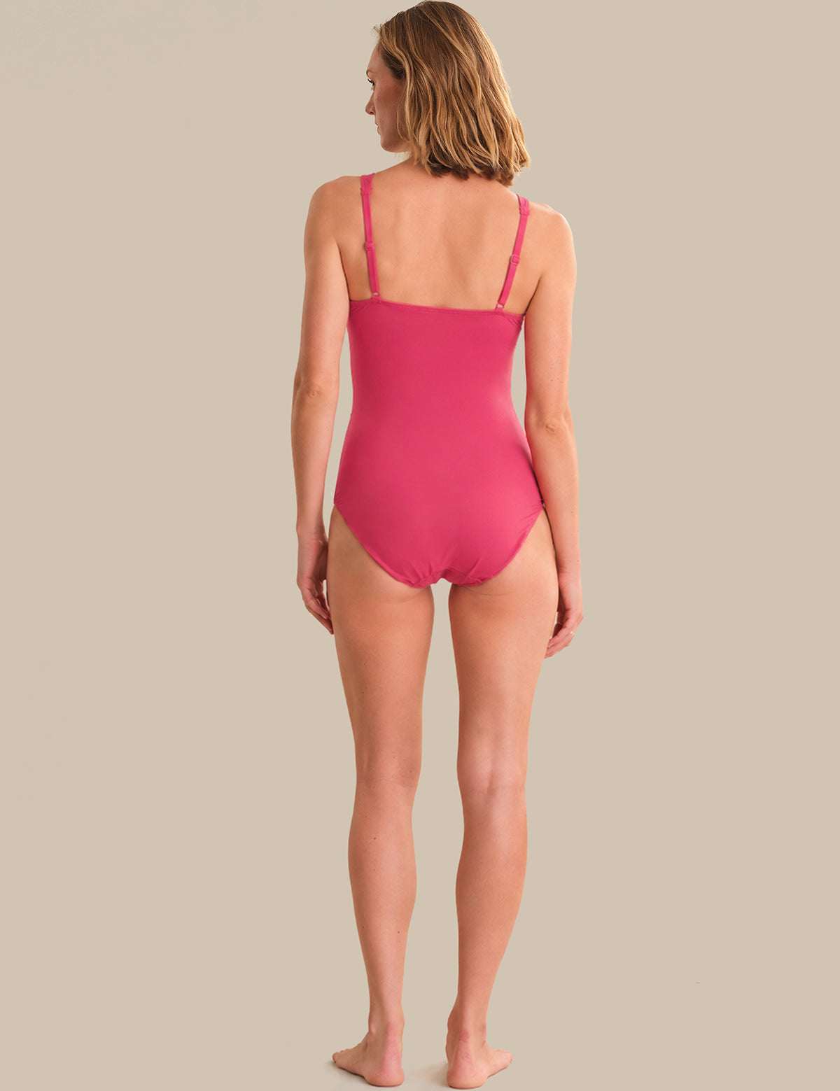 Woman wearing a pink swimsuit on a beige background