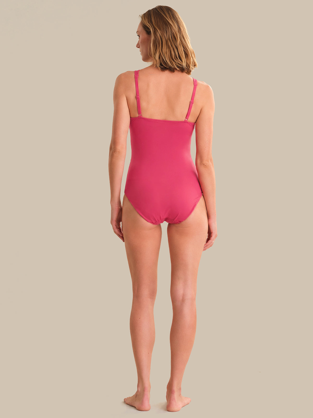 Woman wearing a pink swimsuit on a beige background