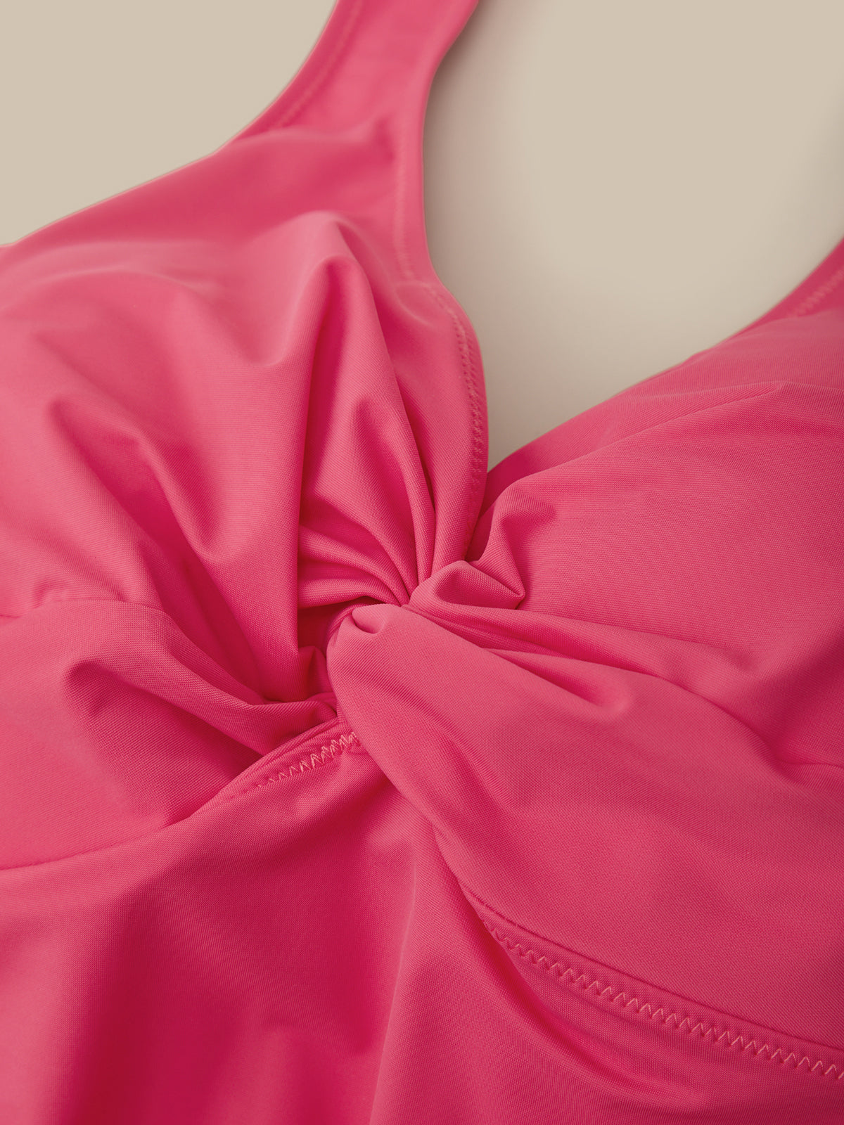 Close-up of a pink swimsuit top on a beige background