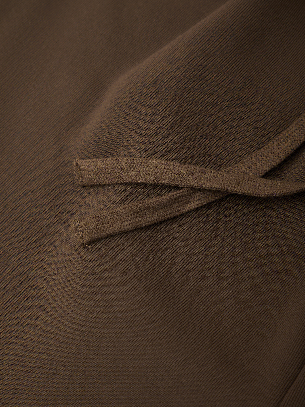 Close-up of a brown fabric surface with matching brown drawstring cords crossing over it.