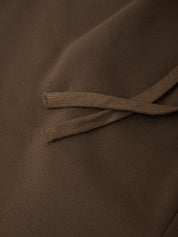 Close-up of a brown fabric surface with matching brown drawstring cords crossing over it.