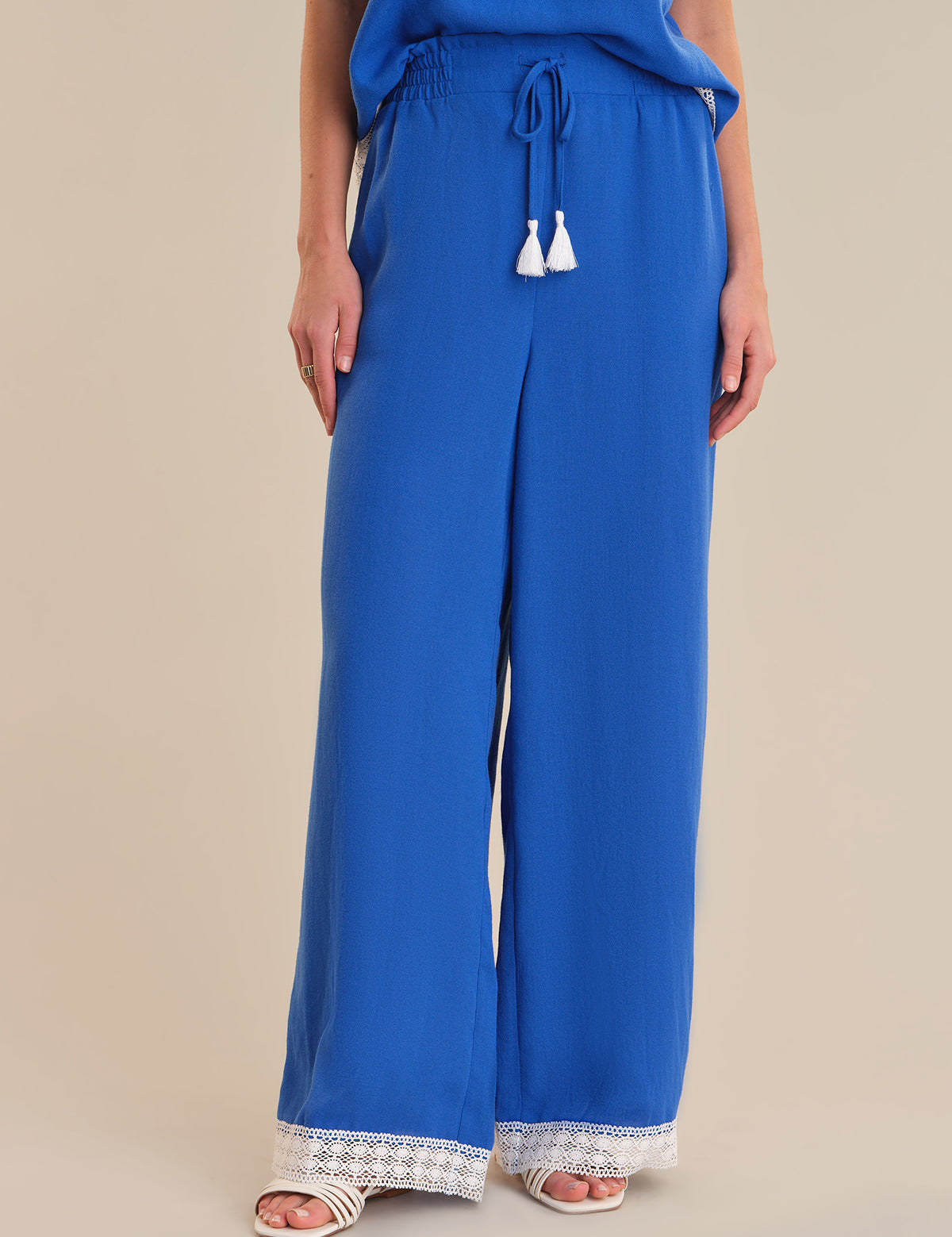 Blue wide-leg pants with lace trim on a beige background