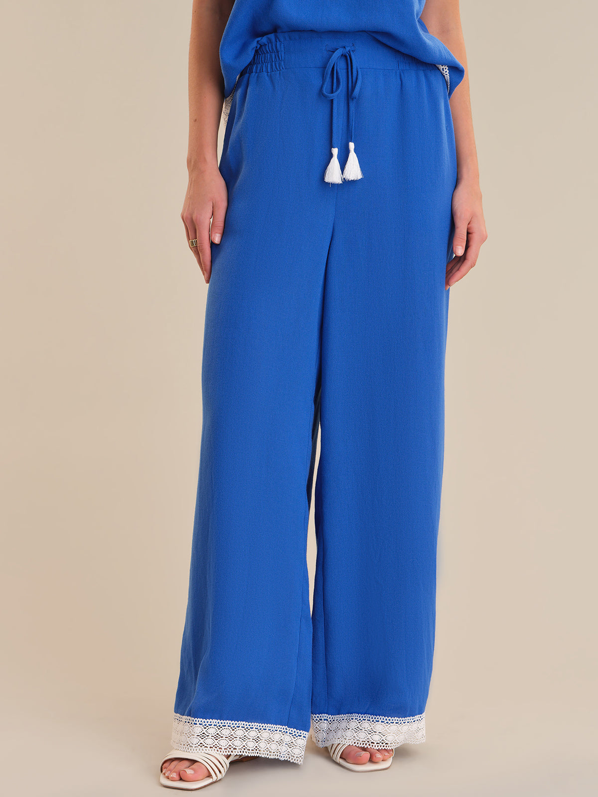 Blue wide-leg pants with lace trim on a beige background