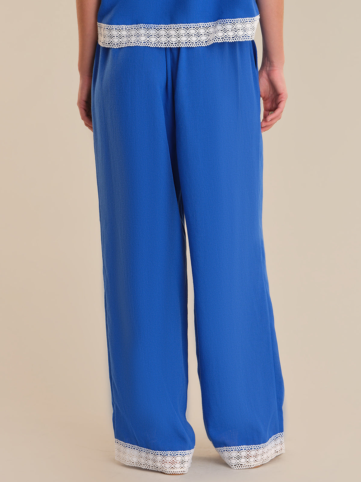 Blue pants with white lace trim on a beige background