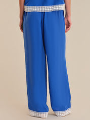 Blue pants with white lace trim on a beige background