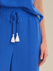 Blue dress with tassel details on a neutral background