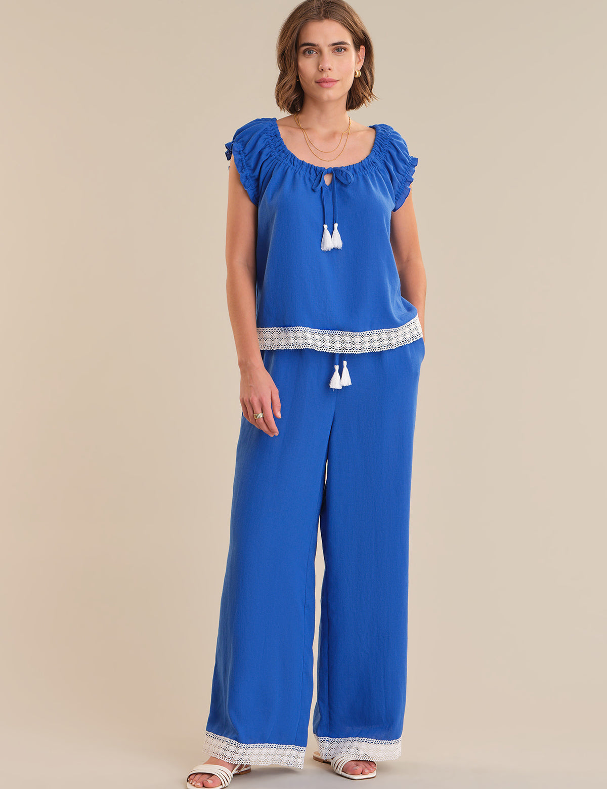 Woman wearing a blue top and wide-leg pants on a beige background