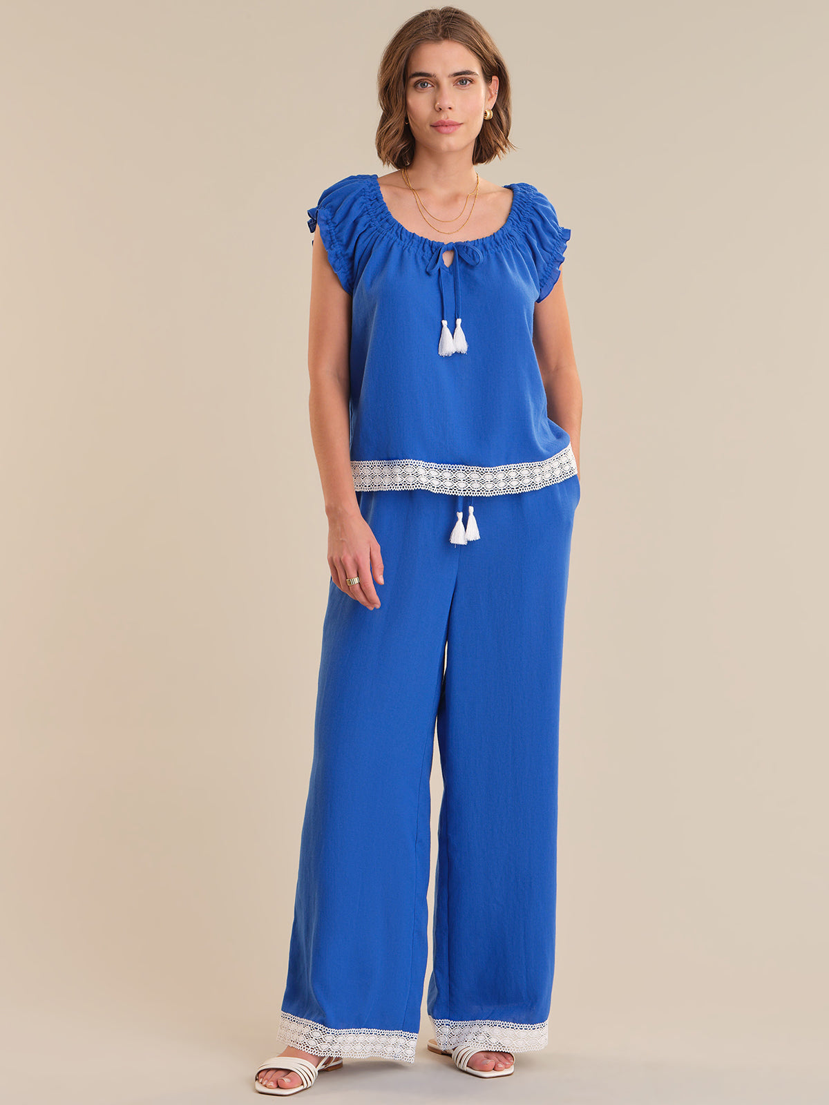 Woman wearing a blue top and wide-leg pants on a beige background