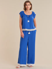 Woman wearing a blue top and wide-leg pants on a beige background