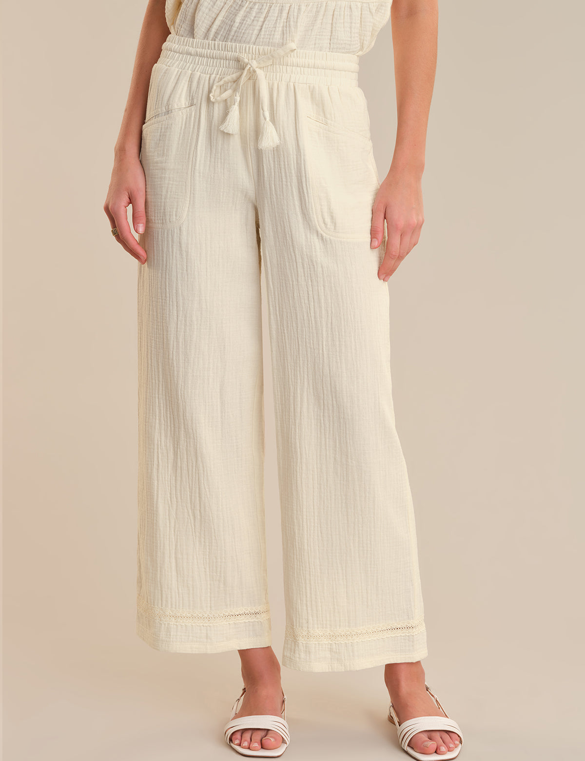 Person wearing cream-colored wide-leg pants on a beige background