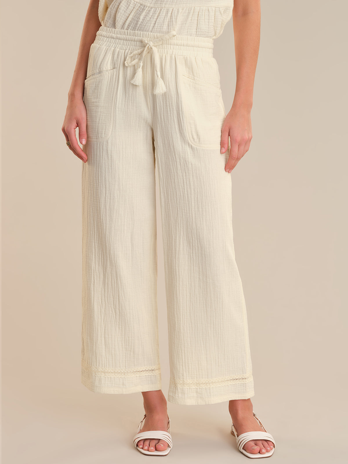 Person wearing cream-colored wide-leg pants on a beige background