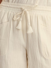 Close-up of beige pants with a drawstring and tassels.