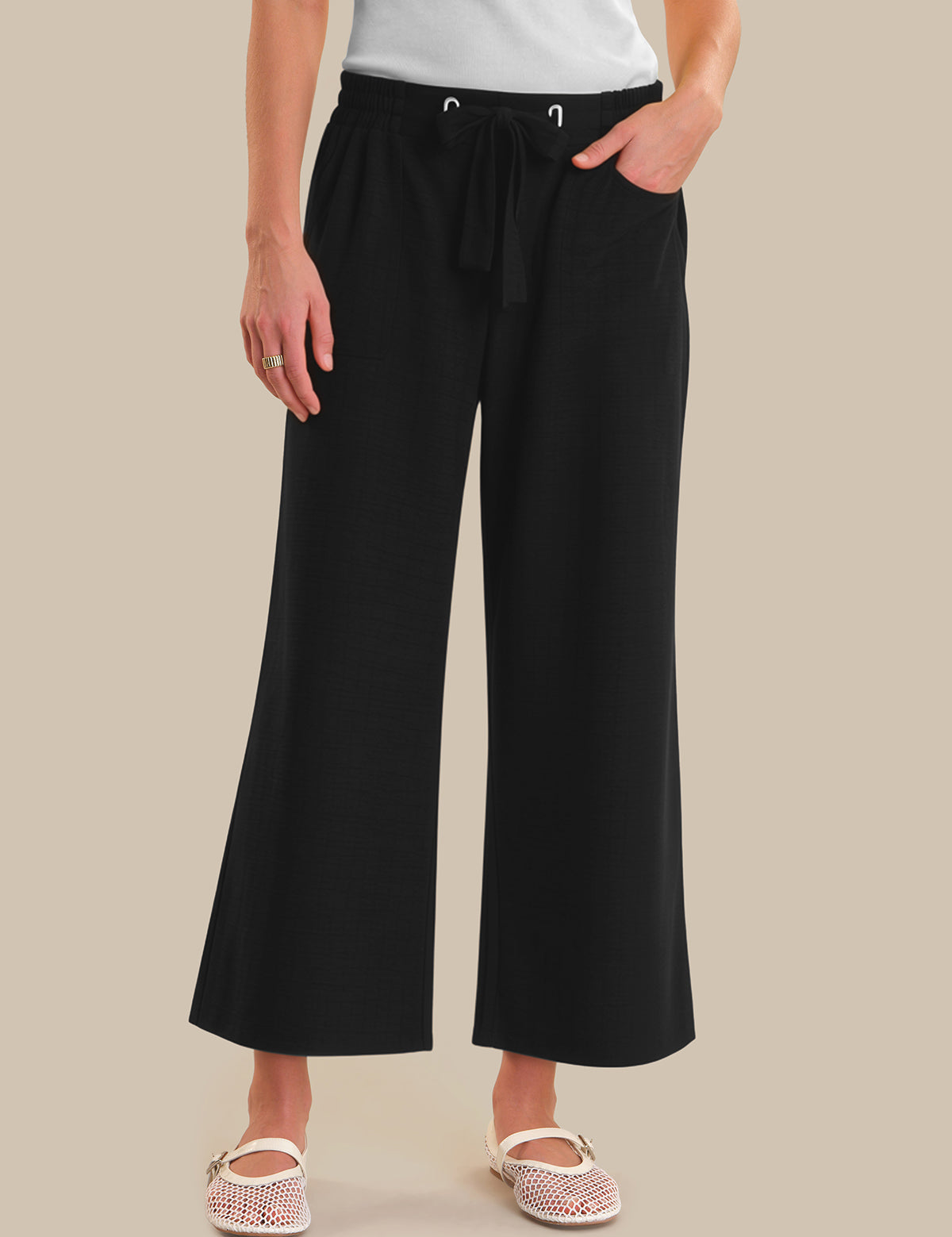 Person wearing black wide-leg pants on a beige background