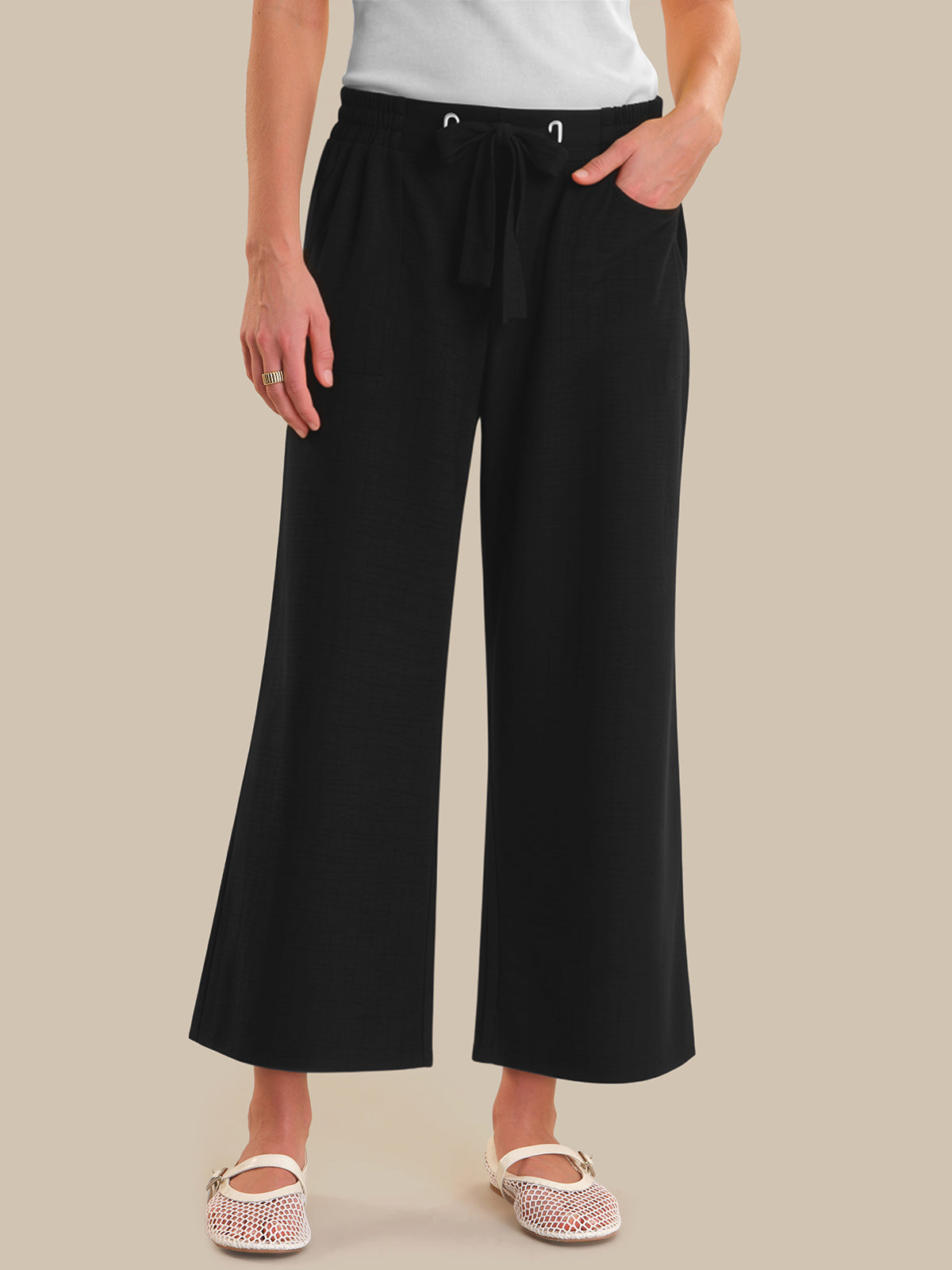 Person wearing black wide-leg pants on a beige background
