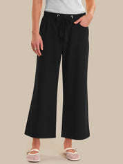 Person wearing black wide-leg pants on a beige background