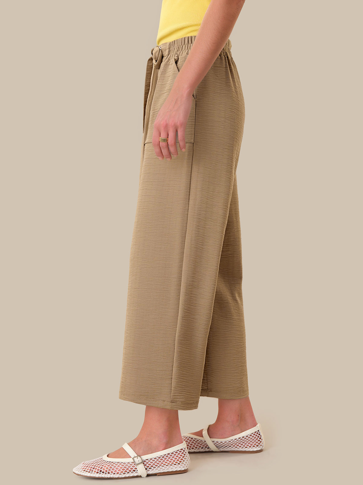 Person wearing beige wide-leg pants on a plain background