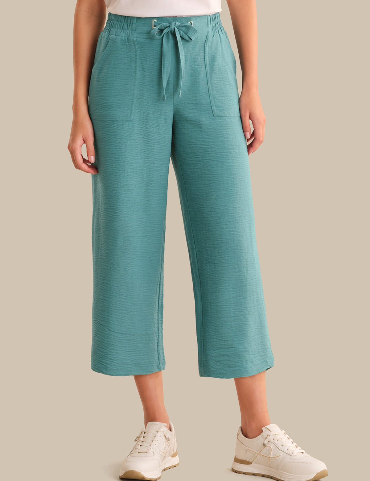 Teal pants worn by a person on a beige background