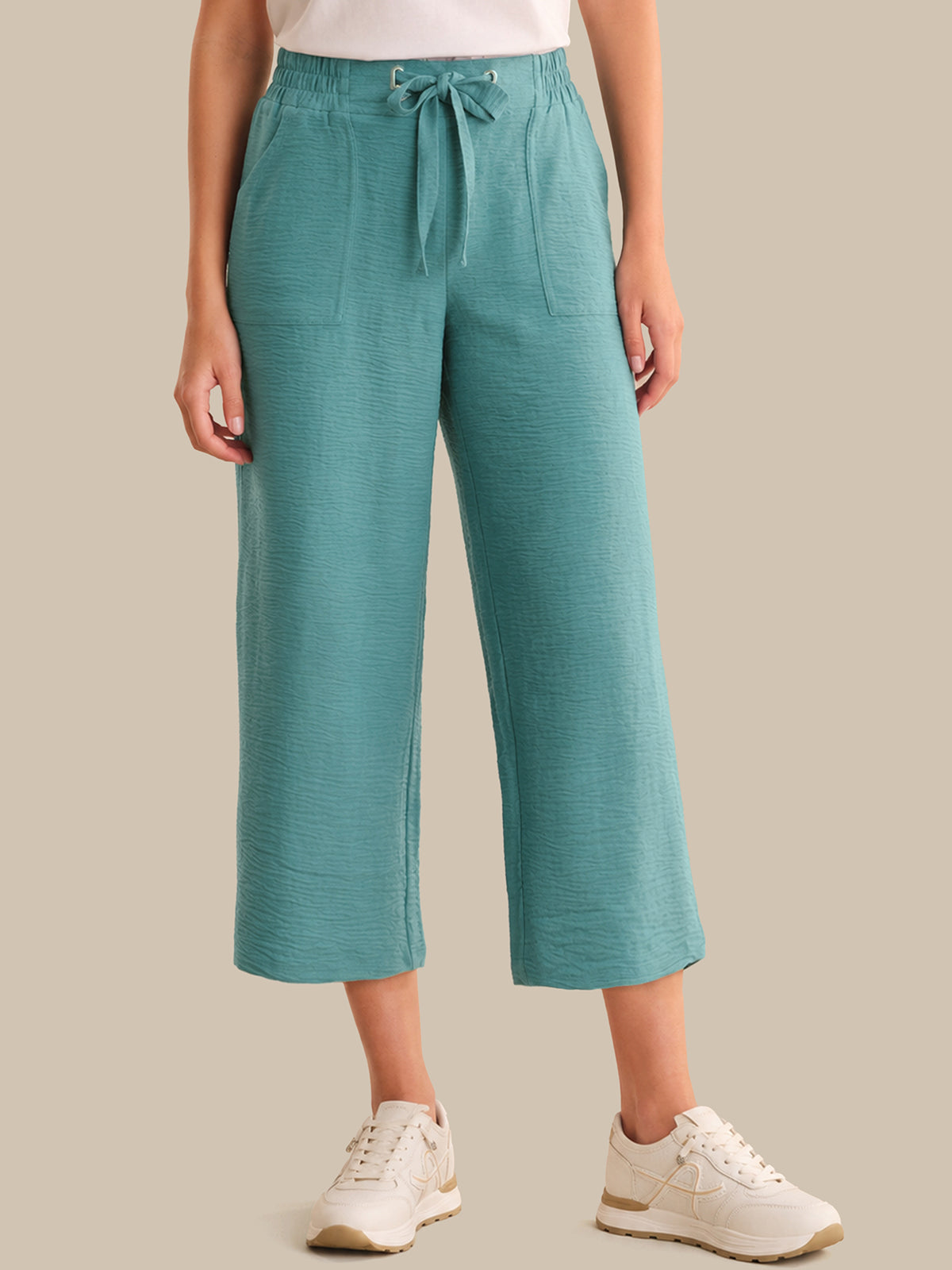 Teal pants worn by a person on a beige background
