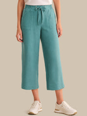 Teal pants worn by a person on a beige background