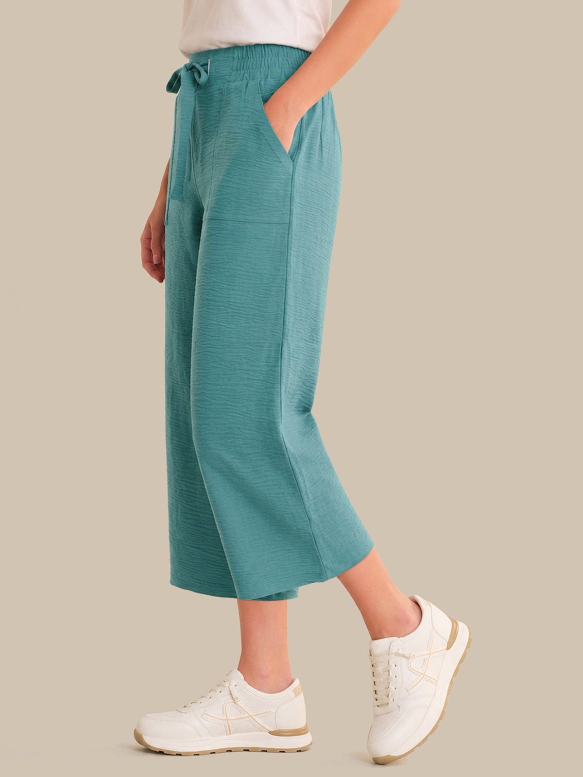 Person wearing teal wide-leg pants with a neutral background