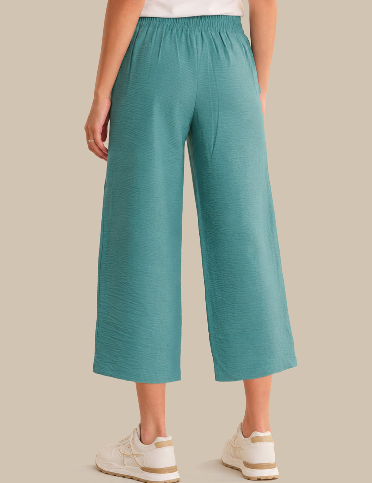 Teal wide-leg pants worn by a person on a beige background