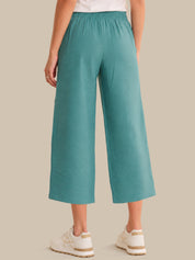 Teal wide-leg pants worn by a person on a beige background