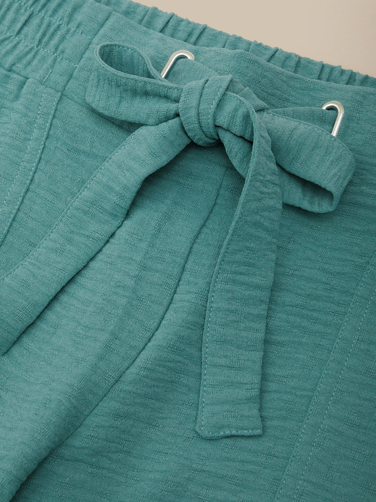 Teal fabric with a bow detail on a beige background