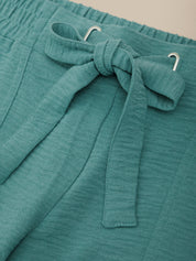 Teal fabric with a bow detail on a beige background