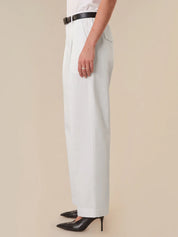 Person wearing light blue pants with a black belt on a beige background