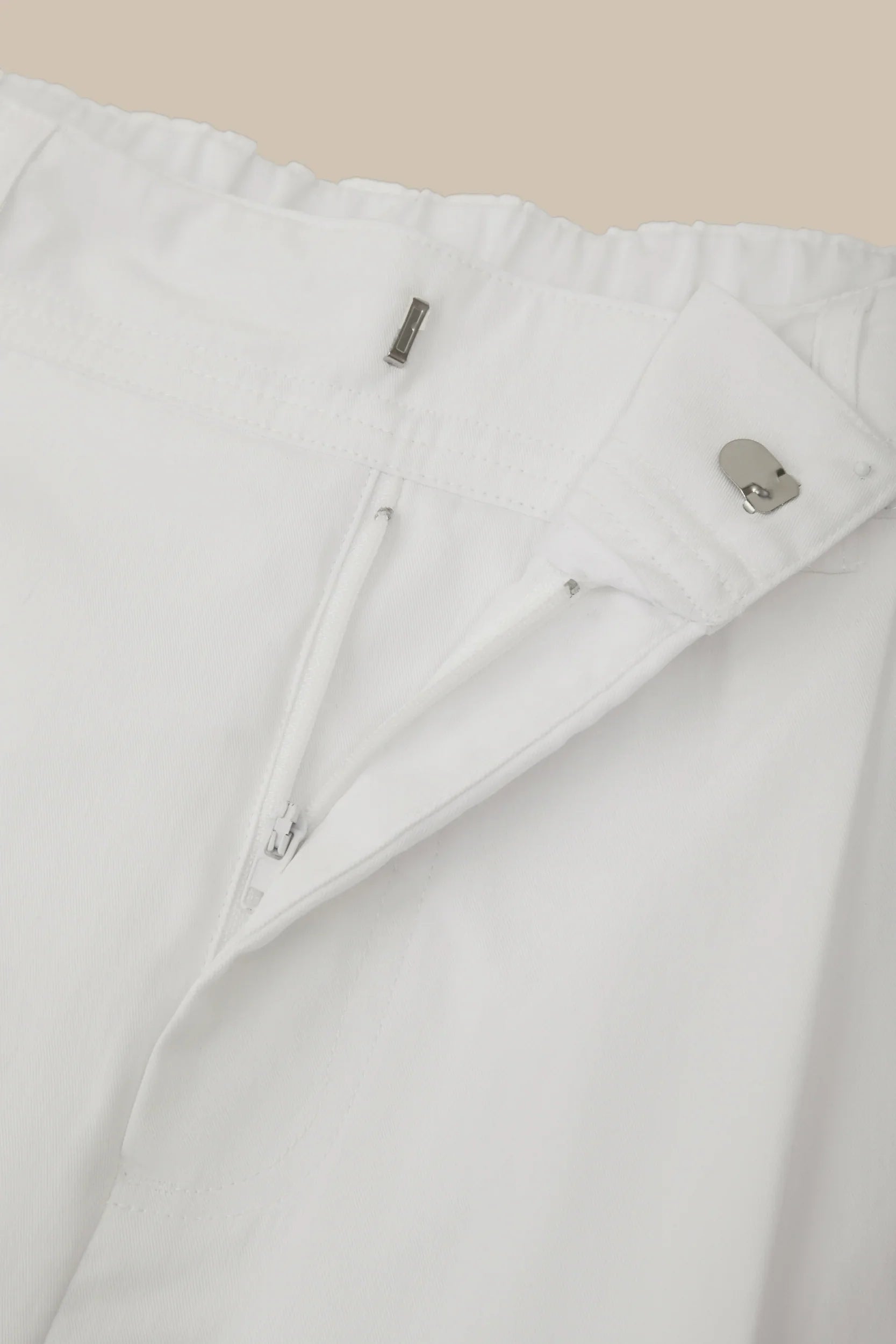 Close-up of a white jacket with zippers on a beige background