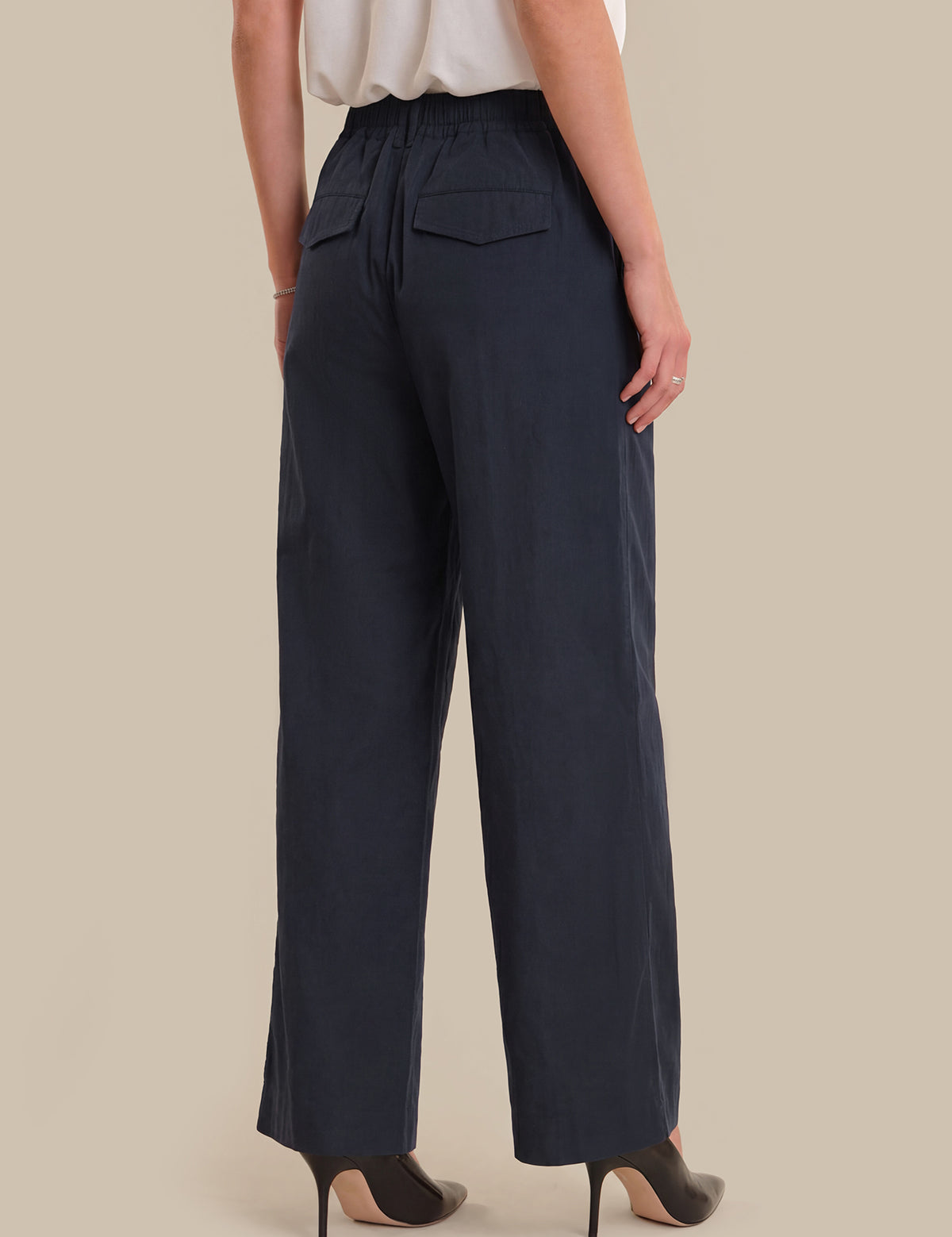 Navy blue wide-leg pants worn by a person on a beige background