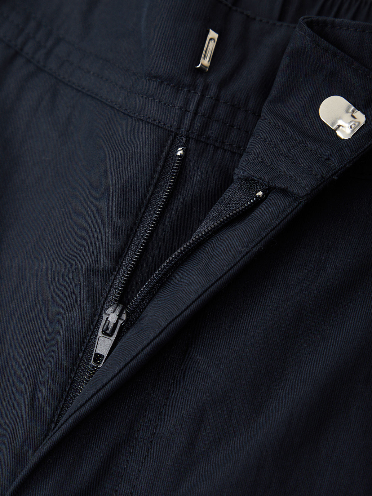 Close-up of a navy blue jacket with zippers and buttons.
